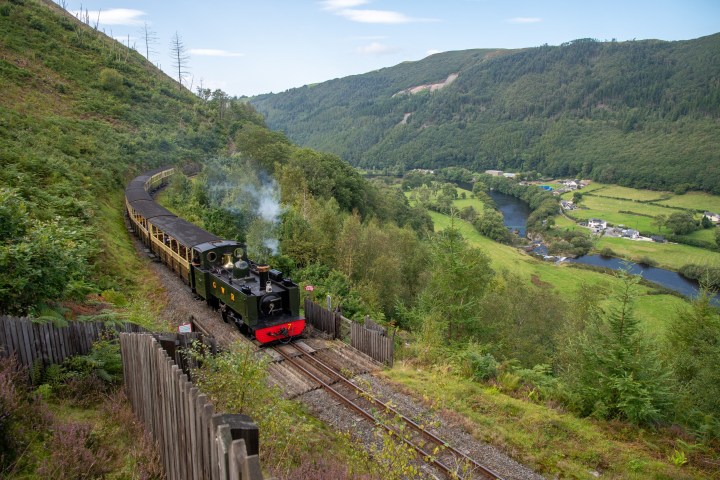 a train traveling down train tracks near a mountain