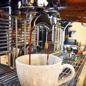 Espresso machine pouring coffee into a ceramic cup.