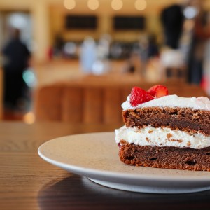 Slice of chocolate cake with cream and strawberries on a plate in a cafe.