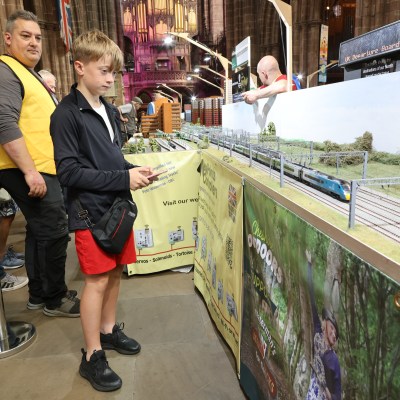 People admire a model train display at an indoor event.