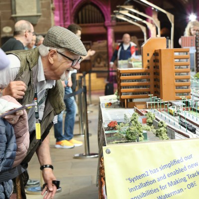 People observing a detailed miniature city model at an exhibition.