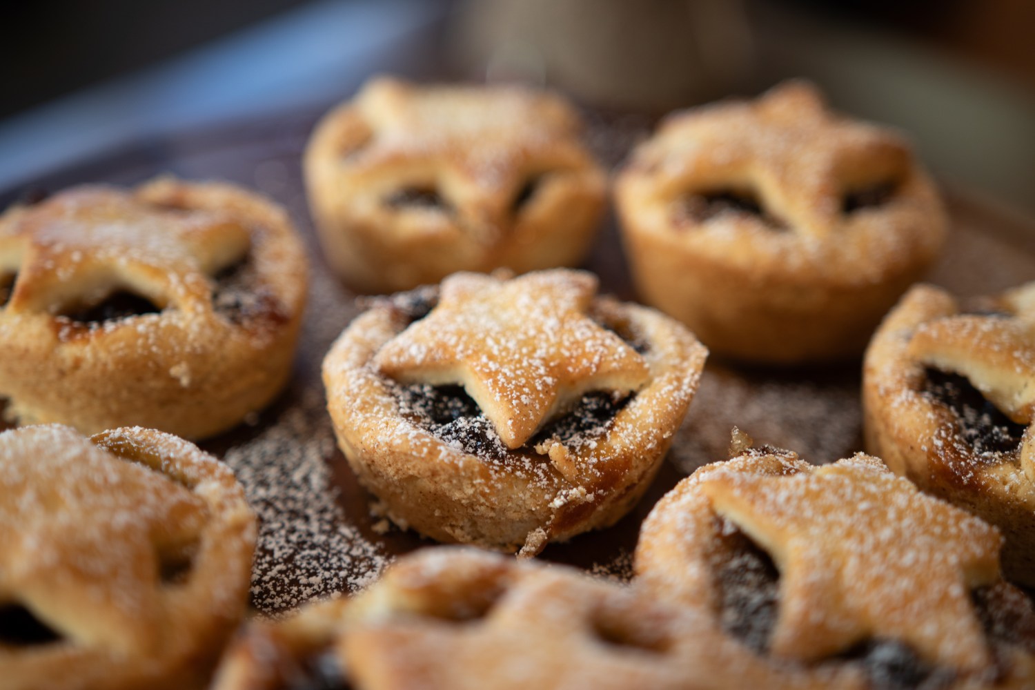 Close-up of star-topped mini pies dusted with powdered sugar on a plate.