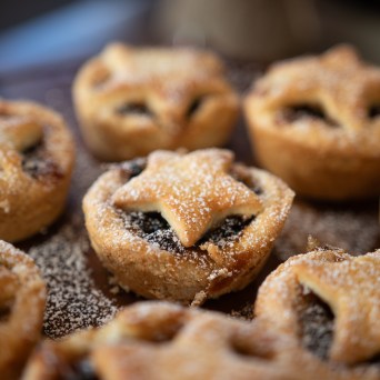 Close-up of star-topped mini pies dusted with powdered sugar on a plate.