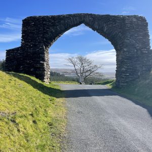 Stone arch over a road with a clear blue sky in the background.