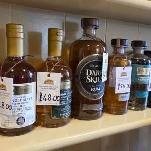 Bottles of various spirits with price tags on a store shelf.