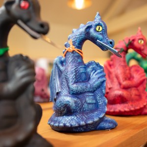 Colorful dragon figurines on a shelf, each holding a sword.