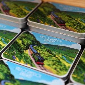 Tin boxes with scenic train imagery stacked on display.