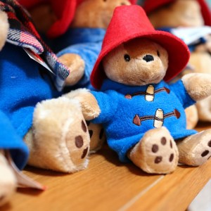 Stuffed bears in blue coats and red hats on a shelf.
