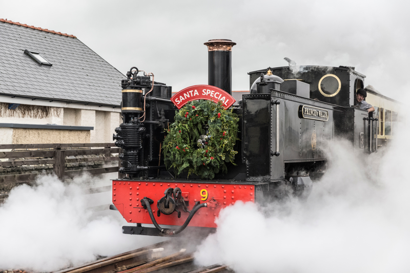 Steam train with 'Santa Special' sign, surrounded by steam.