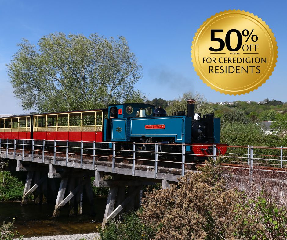 Blue train crossing bridge with discount offer badge saying '50% off for Ceredigion residents'.