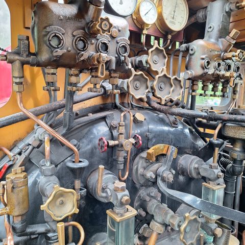 Close-up of vintage machinery with gauges, valves, and metal pipes.