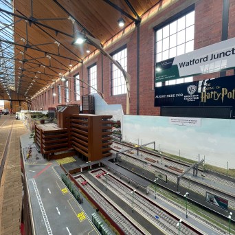 Model railway display at Watford Junction with detailed train tracks and structures in a large hall.