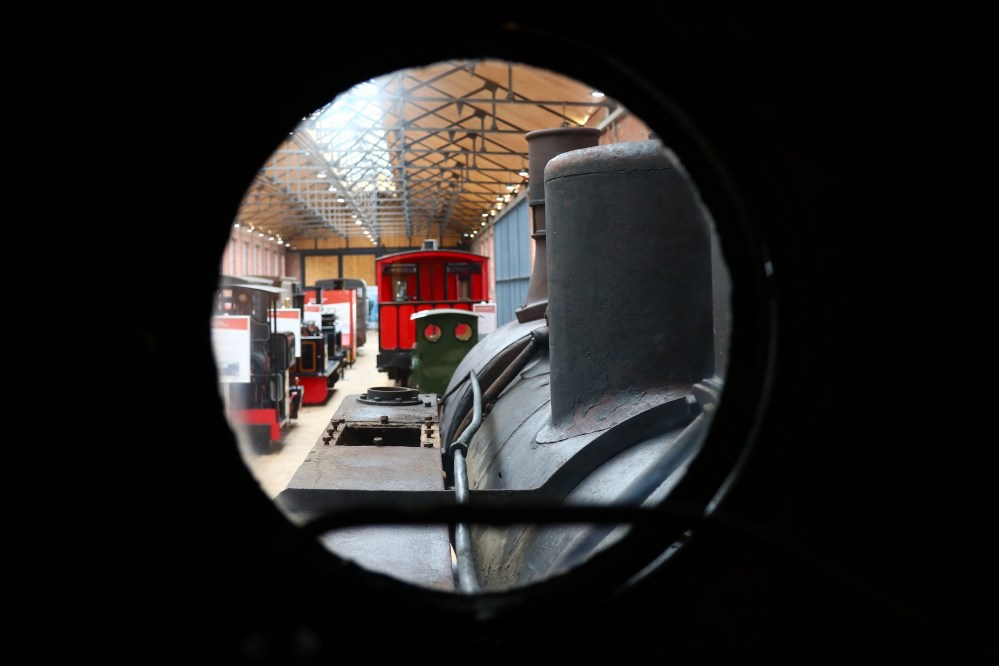 View through a circular window of trains inside a railway museum.