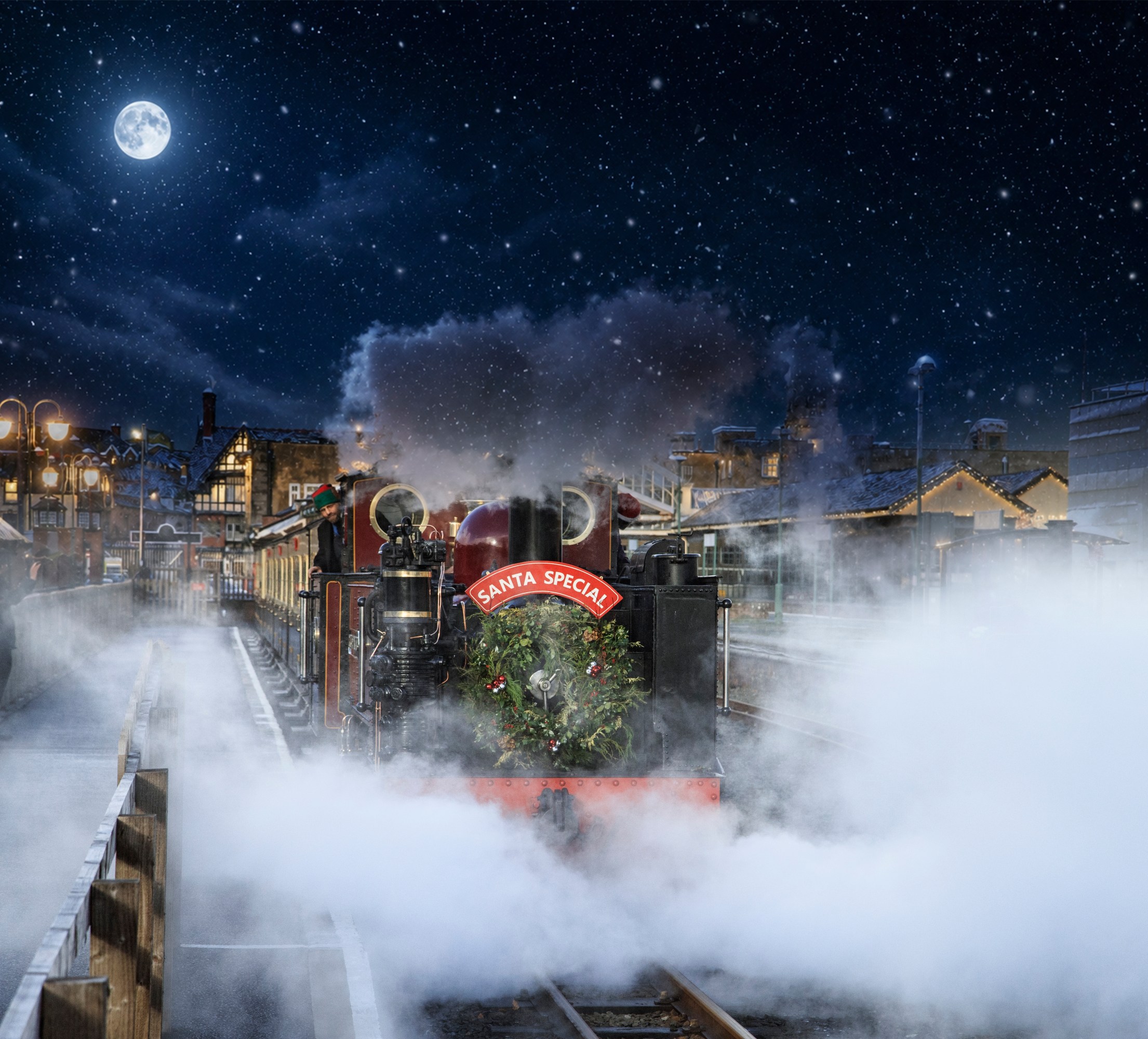 Festive steam train with 'Santa Special' sign at night, snow falling.
