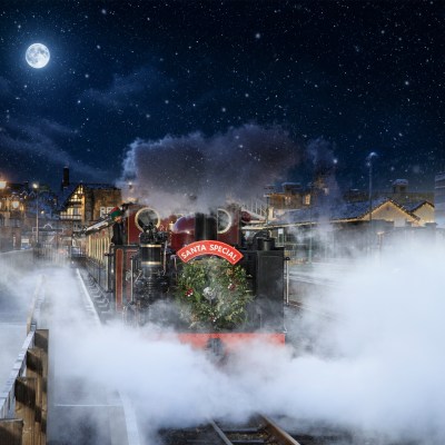 Festive steam train with 'Santa Special' sign at night, snow falling.